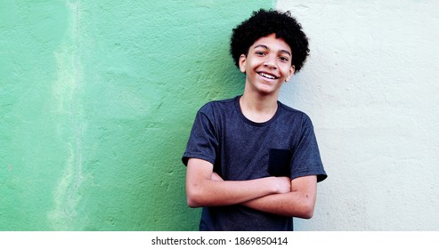 Happy Mixed Race Child Smiling At Camera Leaning On Wall With Arms Crossed