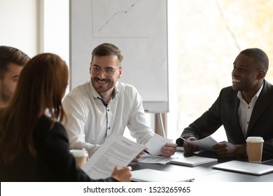 Happy mixed race confident business partners meeting corporate clients, discussing common project ideas. Group of smiling diverse female male employees working together, doing paperwork at workplace. - Shutterstock ID 1523265965