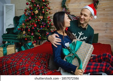 Happy Mixed Race Couple During Christmas With Gift Box At Home.