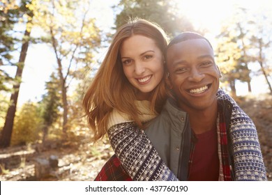 Happy Mixed Race Couple Embracing During Hike In A Forest