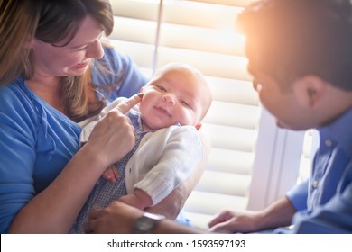 Happy Mixed Race Couple Enjoying Their Newborn Son In The Light of The Window.