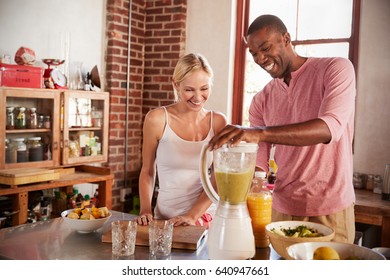 Happy mixed race couple making smoothies, using blender - Powered by Shutterstock