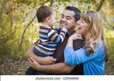 Happy Mixed Race Ethnic Family Having Fun Playing In The Park.