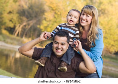 Happy Mixed Race Ethnic Family Posing For A Portrait In The Park.