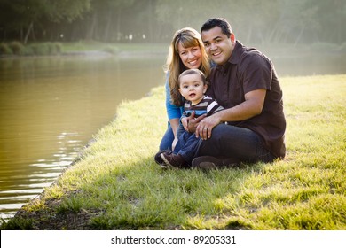 Happy Mixed Race Ethnic Family Posing For A Portrait In The Park By The Lake.