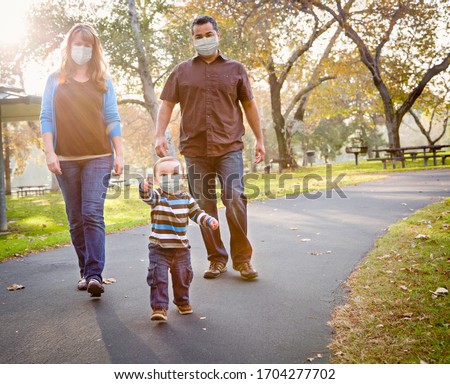 Happy Mixed Race Ethnic Family Walking In The Park Wearing Medical Face Mask.
