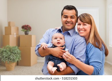 Happy Mixed Race Family With Baby In Room With Packed Moving Boxes.