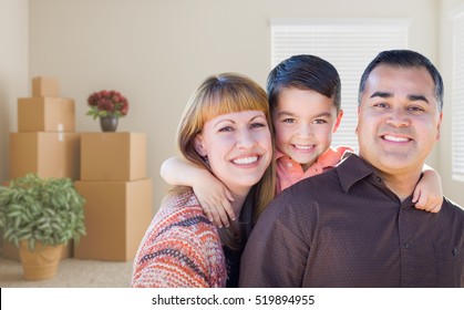 Happy Mixed Race Family With Baby In Room With Packed Moving Boxes.