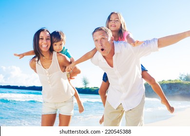 Happy Mixed Race Family Of Four Playing On The Beach