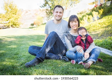 Happy Mixed Race Family Having Fun Outside On The Grass.