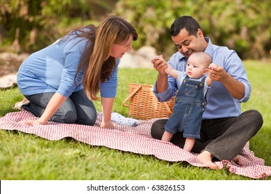 Happy Mixed Race Family Having A Picnic And Playing In The Park.