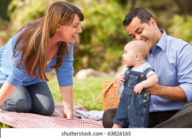 Happy Mixed Race Family Having A Picnic And Playing In The Park.