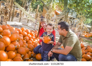 Happy Mixed Race Family Picking Pumpkins At The Pumpkin Patch.