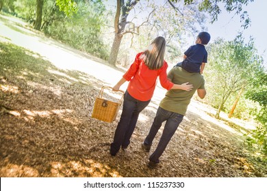 Happy Mixed Race Family With Picnic Basket Enjoy A Walk In The Park.