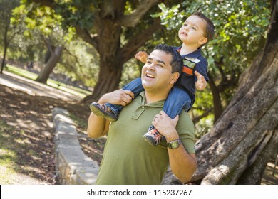 Happy Mixed Race Son Enjoys A Piggy Back Ride In The Park With Dad.