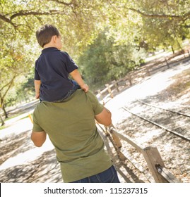 Happy Mixed Race Son Enjoys A Piggy Back Ride In The Park With Dad.