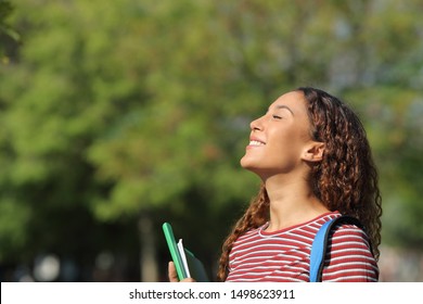 Happy mixed race student breathing deeply fresh air standing in a park or campus - Powered by Shutterstock