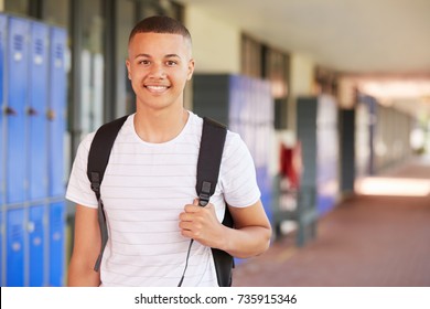 Happy mixed race teenage boy smiling in high school corridor