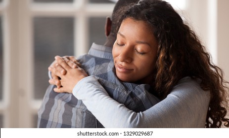 Happy mixed race woman hug black man husband glad to make peace after fight, loving young girlfriend reconcile with beloved boyfriend, embracing holding in arms. Healthy relationships concept