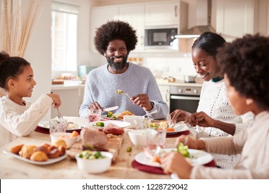 Happy Mixed Race Young Family Of Four Eating Sunday Dinner Together, Front View