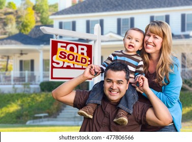 Happy Mixed Race Young Family In Front Of Sold Home For Sale Real Estate Sign And House.