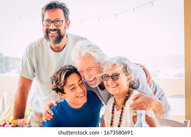 Happy Mixed Three Generations Family Hug And Enjoy Together - People Group Portrait With Senior Adult And Teenager Together - Bright Sky Background And Cheerful Smiles