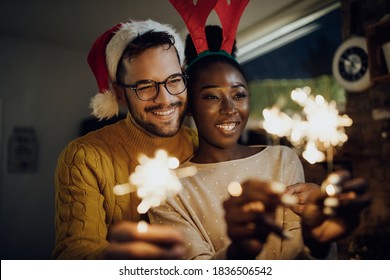 Happy mixed-race couple celebrating New Year and having fun with sparklers at home. - Powered by Shutterstock