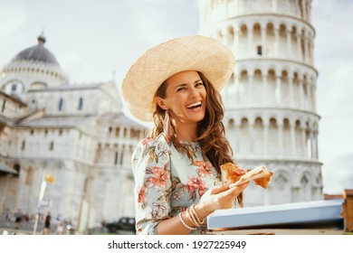 happy modern middle aged traveller woman in floral dress with pizza and hat near Leaning Tower in Pisa, Italy.