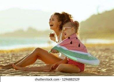 Happy Modern Mother And Child In Swimwear On The Seashore In The Evening Having Fun Time Wrapped In Watermelon Towel. Minimal To No Crowd Peace. Fun Beach-friendly Activities For The Whole Family.