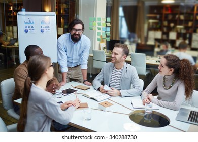 Happy Modern Office Workers Discussing Plans And Ideas At Meeting