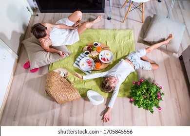 Happy Mom And Boy Imitating Summer Picnic Time On Green Grass Blanket Near TV Screen. Travelling With Family. Coronavirus Situation In Tourism Industry. Quarantine. Stay At Home. Isolation. Top View