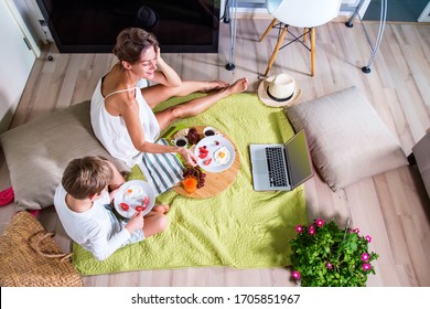 Happy mom and boy imitating summer picnic time with father online near computer .Travelling with family. Coronavirus situation in tourism industry. Quarantine. Stay at home. Isolation. Top view
