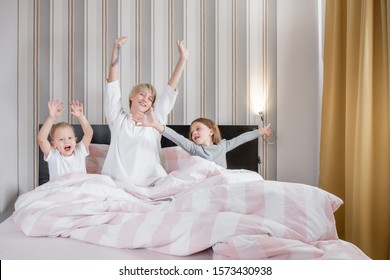 Happy Mom And Children Are Resting From School And Work On The Day Off. Concept Of Rest And Relaxation At Home On The Weekend. Mom And Children Rejoice In The Coming New Year. Joint Weekend Concept