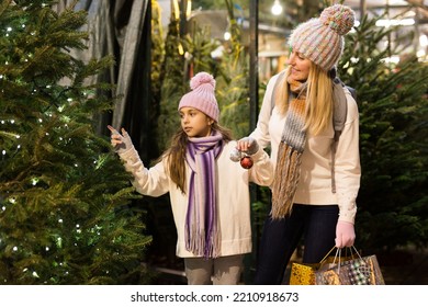 Happy mom and daughter choose christmas tree at street market