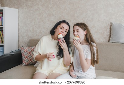 Happy Mom And Daughter Eating Delicious Strawberry Shortcake Sitting At Home On The Couch. Family Happiness Is Joy.