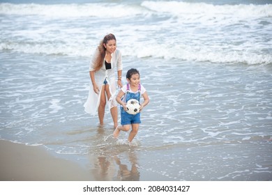 Happy Mom And Daughter Having Fun Playing Soccer On The Beach. Happy Family Having Fun Running On Beach. Relaxing Holiday Concept. Travel Attention