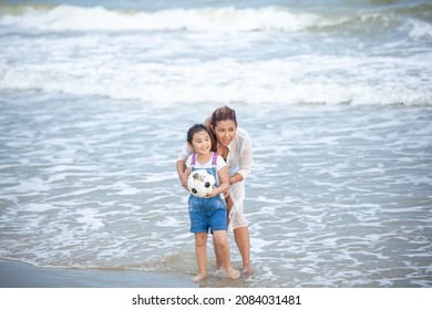 Happy Mom And Daughter Having Fun Playing Soccer On The Beach. Happy Family Having Fun Running On Beach. Relaxing Holiday Concept. Travel Attention