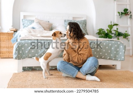 Happy mom and daughter play with their adorable wired Jack Russell Terrier puppy at home. Loving family with a puppy in the bedroom. Background, close-up, copy space.