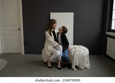 Happy Mom With Glasses And A Preschool-age Son, Hugging And Smiling On A Dark Background. A Family Of Two. Portrait Of Interesting People.