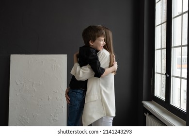 Happy Mom With Glasses And A Preschool-age Son, Hugging And Smiling On A Dark Background. A Family Of Two. Portrait Of Interesting People.