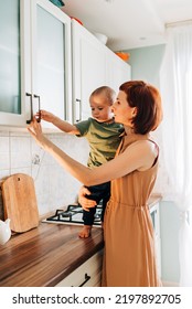 Happy Mom With Her Child Cooking At The Kitchen. Cozy Home And Routine Duties