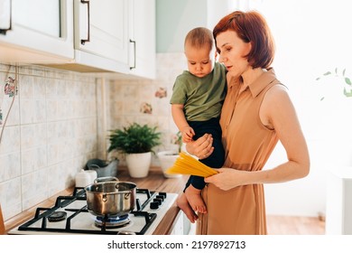 Happy Mom With Her Child Cooking At The Kitchen. Cozy Home And Routine Duties