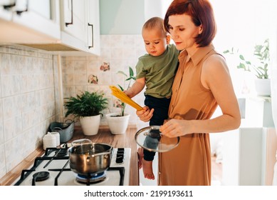 Happy Mom With Her Child Cooking At The Kitchen. Cozy Home And Routine Duties