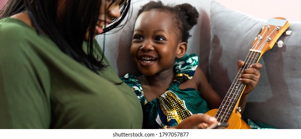 Happy Mom With Her Daughter Playing Guitar And Singing Together At Home, Happy Family