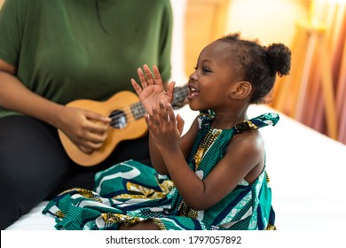 Happy Mom With Her Daughter Playing Guitar And Singing Together At Home, Happy Family