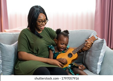 Happy Mom With Her Daughter Playing Guitar And Singing Together At Home, Happy Family