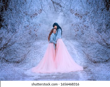 Happy mom hugs daughter in fabulous winter forest. Queen long black hair, princess brunette . Family in luxurious long puffy dress, warm scarf sweater. Backdrop nature covered hoarfrost snow ice frost