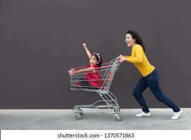 Happy Mom And Kid Go Shopping Cart Together. Funny Action Of Mother And Child Go To Modern Trade Or Shopping Center With Cart  