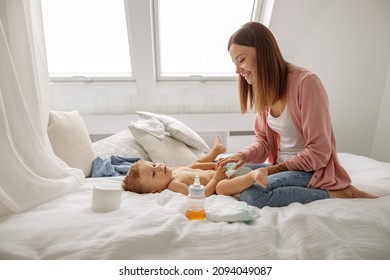 Happy mom putting diaper on her baby in nursery - Powered by Shutterstock