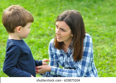 Glückliche Mutter und Sohn spielen im Frühling im Park. Mutter spricht mit ihrem Sohn im Park
